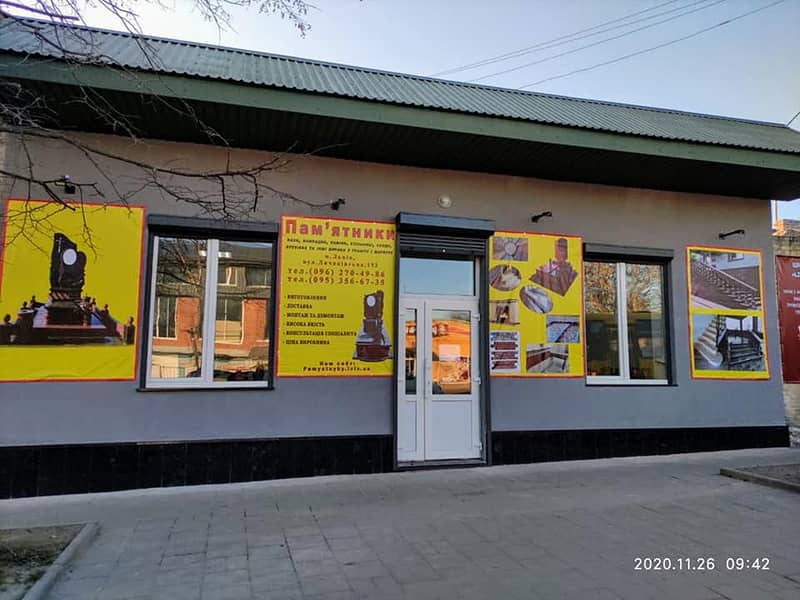 Фасад та територія магазину Граніт у Львові. Банери з гранітними виробами на фасаді